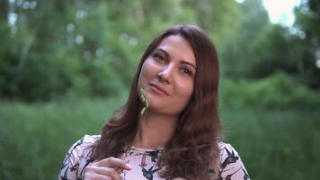 Beautiful happy girl with long hair is standing in the forest with summer sunny weather. Portrait video