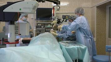 surgeons a man and two women in a large operating room perform microscopic surgery on ENT organs using a surgical microscope.Innovative technologies in medicine video