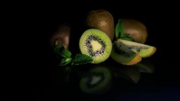 Fruit kiwi and mint leaves lie on a table on a black background. HD video