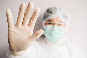 Nurse wearing PPE suit for protect virus and show stop hand gesture for social distancing. Social distancing is the physical space between people to avoid spreading illness. photo