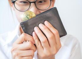 Happiness woman holding and looking leather wallet with a golden Bitcoin token in her hands. photo