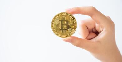 Someone hand holding a golden Bitcoin token isolated on white background. Bitcoin is one of the popular cryptocurrency, a virtual currency or a digital currency. photo