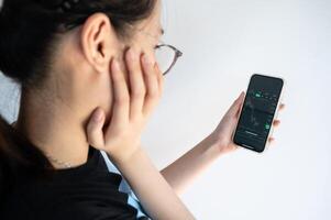 Woman checking Bitcoin price chart on digital exchange on her smartphone. A cryptocurrency exchange is an online marketplace where users buy, sell, and trade. photo