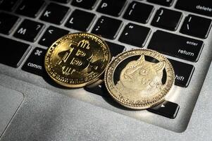 Bitcoin and Dogecoin tokens on computer keyboard. photo