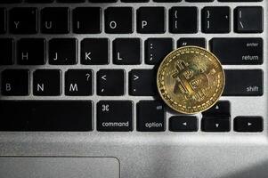 A golden bitcoin token on computer keyboard. photo