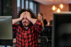 Disappointed Programmer with Messy Hair Looking at Computer Monitor in Office. photo