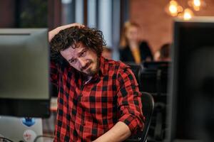 Disappointed Programmer with Messy Hair Looking at Computer Monitor in Office. photo