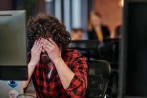Disappointed Programmer with Messy Hair Looking at Computer Monitor in Office. photo