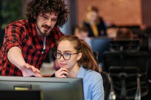 Business colleagues, a man and a woman, engage in discussing business strategies while attentively gazing at a computer monitor, epitomizing collaboration and innovation photo