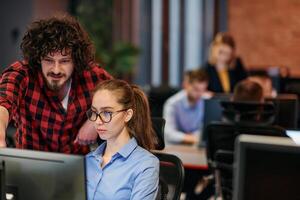 Business colleagues, a man and a woman, engage in discussing business strategies while attentively gazing at a computer monitor, epitomizing collaboration and innovation photo
