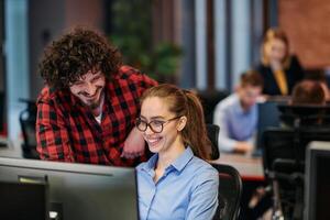Business colleagues, a man and a woman, engage in discussing business strategies while attentively gazing at a computer monitor, epitomizing collaboration and innovation photo