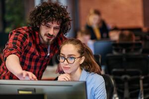 Business colleagues, a man and a woman, engage in discussing business strategies while attentively gazing at a computer monitor, epitomizing collaboration and innovation photo