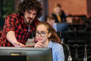 Business colleagues, a man and a woman, engage in discussing business strategies while attentively gazing at a computer monitor, epitomizing collaboration and innovation photo