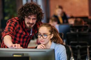 Business colleagues, a man and a woman, engage in discussing business strategies while attentively gazing at a computer monitor, epitomizing collaboration and innovation photo