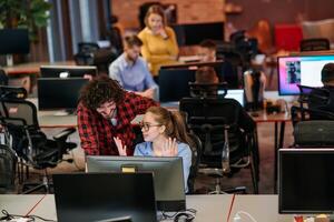 Business colleagues, a man and a woman, engage in discussing business strategies while attentively gazing at a computer monitor, epitomizing collaboration and innovation photo