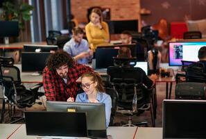 Business colleagues, a man and a woman, engage in discussing business strategies while attentively gazing at a computer monitor, epitomizing collaboration and innovation photo