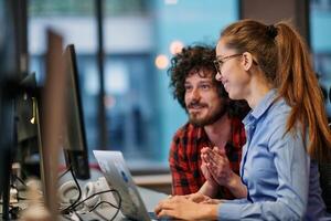 Business colleagues, a man and a woman, engage in discussing business strategies while attentively gazing at a computer monitor, epitomizing collaboration and innovation photo