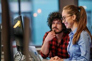Business colleagues, a man and a woman, engage in discussing business strategies while attentively gazing at a computer monitor, epitomizing collaboration and innovation photo