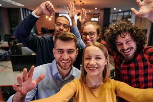 A diverse group of business professionals take a break from their tasks in a modern startup office to capture a creative selfie, showcasing teamwork and a vibrant workplace culture photo