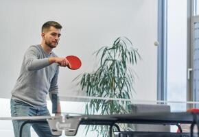 Business colleagues take a break from work to enjoy a game of table tennis, fostering teamwork and camaraderie in the workplace photo