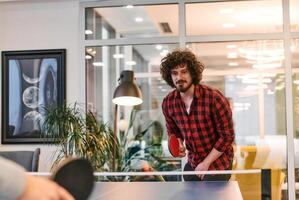 Business colleagues take a break from work to enjoy a game of table tennis, fostering teamwork and camaraderie in the workplace photo