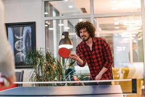 Business colleagues take a break from work to enjoy a game of table tennis, fostering teamwork and camaraderie in the workplace photo