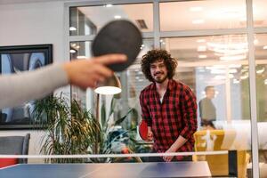 Business colleagues take a break from work to enjoy a game of table tennis, fostering teamwork and camaraderie in the workplace photo