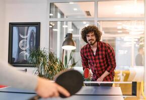 Business colleagues take a break from work to enjoy a game of table tennis, fostering teamwork and camaraderie in the workplace photo