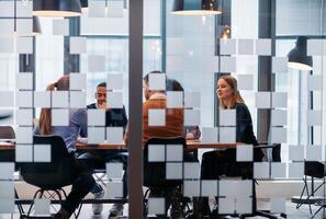 In a sleek glass office space, a team of business professionals engage in lively discussions and exchange strategic ideas, showcasing collaboration and innovation at the heart of modern corporate photo
