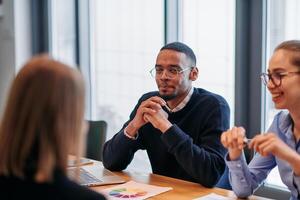 In the vibrant ambiance of a modern startup office, a diverse team of business professionals engage in discussions on various projects and develop new business strategies, epitomizing creativity and photo