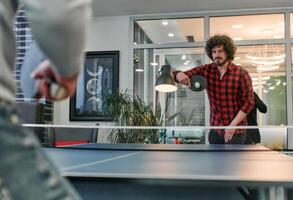 Business colleagues take a break from work to enjoy a game of table tennis, fostering teamwork and camaraderie in the workplace photo