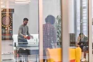 Business colleagues take a break from work to enjoy a game of table tennis, fostering teamwork and camaraderie in the workplace photo