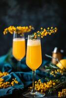 Two Glasses of Sparkling Orange Mimosa With Yellow Flowers on Blue Fabric photo