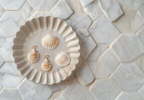 Seashell Earrings on White Hexagon Tile Background With Eucalyptus photo