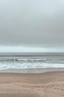 Coastal Scene With Waves Crashing on Sandy Beach Under a Cloudy Sky photo