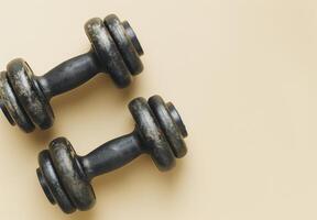 Black Cast Iron Dumbbell With Knurled Handle On Tan Background photo