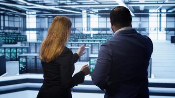 Teamworking admin colleagues inspecting server room hardware. IT expert and colleague supervising data center establishment, checking equipment, monitoring performance, camera A video