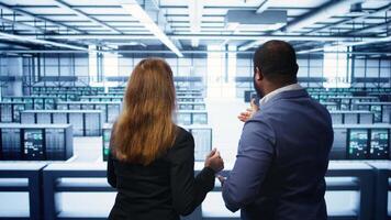 Teamworking admin colleagues inspecting server room hardware. IT expert and colleague supervising data center establishment, checking equipment, monitoring performance, camera B video