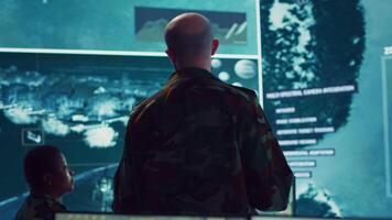 Army officer examining real time satellite data on big screen in military power base, gather intelligence on enemy vessels trajectory. Federal defense program specialist commanding troops. Camera A. video
