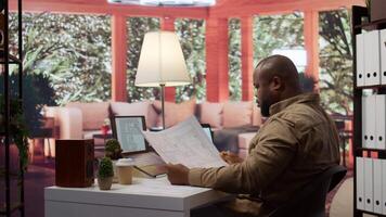 Business owner conducting strategic research on office spaces and building layouts, using blueprints and sketches to draft and organize a new creative workspace. Office hunt relocation. Camera B. video