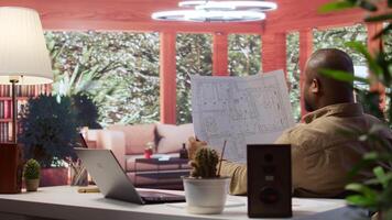 Entrepreneur analyzing architectural sketches and blueprints at his home, planning the layout and design of a new office to foster business development. Hunting for creative workspace. Camera B. video