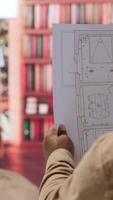 Vertical Entrepreneur analyzing architectural sketches and blueprints at his home, planning the layout and design of a new office to foster business development. Hunting for creative workspace. Camera A. video