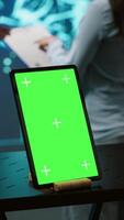 Vertical Green screen tablet used by computer scientists in startup doing advancements in AI field. Employees working on mockup device in workspace featuring artificial intelligence systems, camera A video