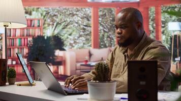 Freelancer managing startup projects and thinking about client needs from his home office, developing new growth strategy. Self employed analyst does telecommuting work on laptop. Camera B. video
