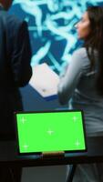 Vertical AI programmers colleagues using green screen laptop for business data analysis. IT experts in high tech location work on chroma key notebook to automatize tasks using artificial intelligence, camera A video