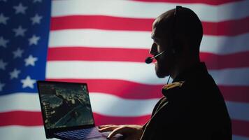 US Air Force dispatcher looking at surveillance transmission on device, relaying data to ground soldiers from control room using headset, isolated over United States flag background, camera B video