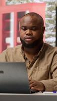 Vertical Freelancer writing business reports and managing finance on his laptop, home based work strategies. Entrepreneur works on remote job management and financial analysis, self employed. Camera A. video