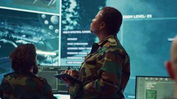 Woman high tech specialist studying satellite CCTV visualization on a big screen, preparing troops with insight for a new national safety mission. Female first lieutenant in command post. Camera A. video