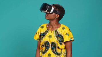 Young happy woman working with a virtual reality headset in studio, using the innovative 3d simulation experience with modern equipment. VR glasses on girl in traditional ethnic clothes. Camera A. video