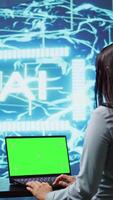 Vertical IT specialist using green screen laptop and AI technology for business data analysis in high tech setting. Engineer works on mockup notebook to automatize tasks using artificial intelligence, camera B video